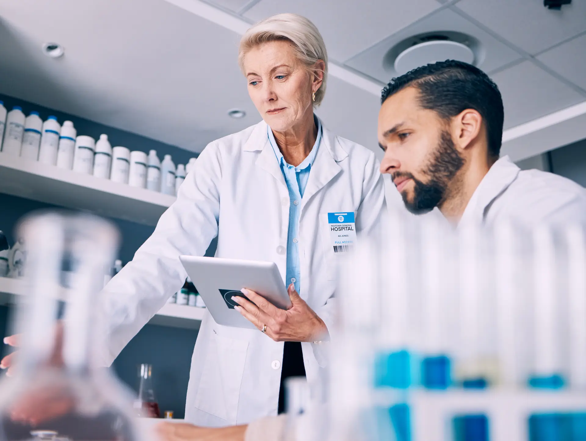 male and female pharmacist looking over something at a work bench